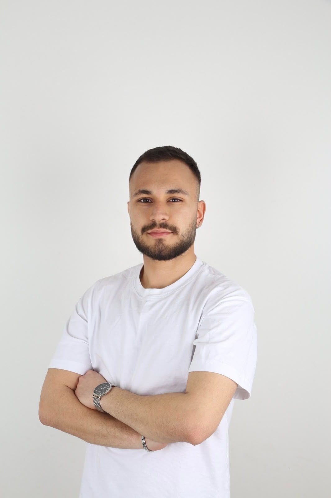 Psikolog Eren Yener, beyaz tişörtle kollarını kavuşturmuş, gülümseyerek kameraya bakıyor